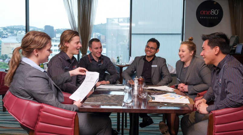 Hotel employees sitting around a table discussing a document