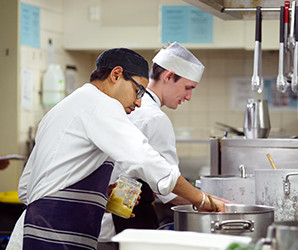 Two workers preparing food in kitchen