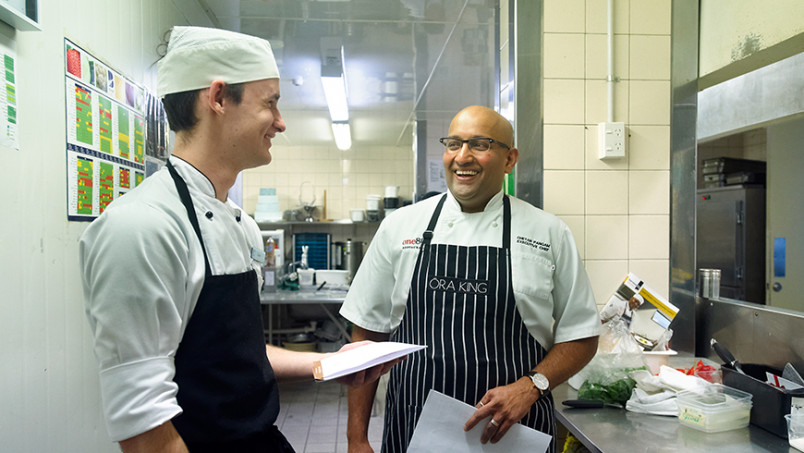 Two chefs laughing in kitchen