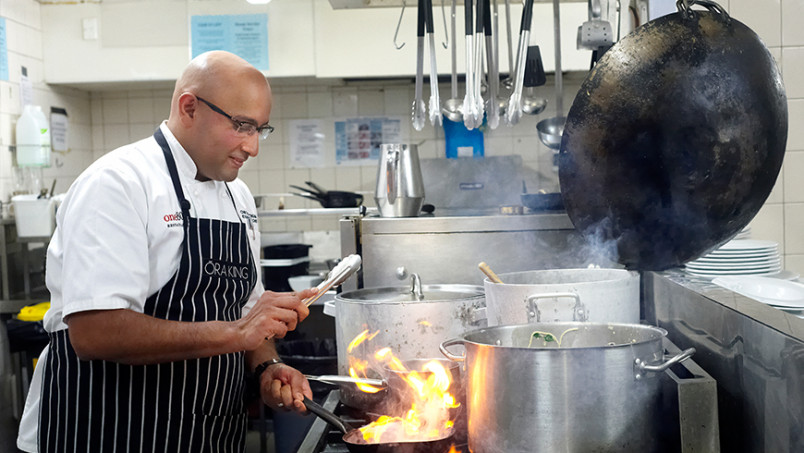 Migrant chef in kitchen preparing food