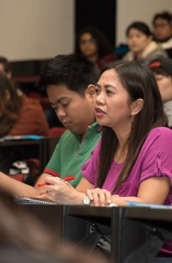 Woman sitting in lecture theatre with other students in the background