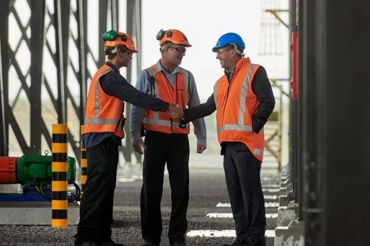 three engineers meet on-site, in safety gear